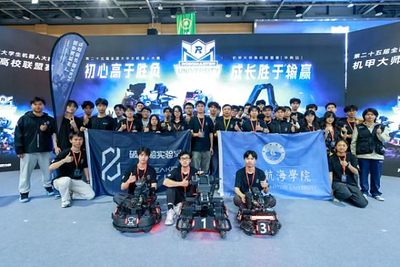 ICBK 破冰船战队在 RMUL 2026 华南站背景板前合影，手持队旗与校旗，前方摆着参赛机器人